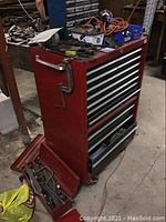 Front view of red metal tool chest with drawers and toolbox on floor