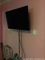Haier 32 inch flat screen TV wall mounted with cables hanging down.