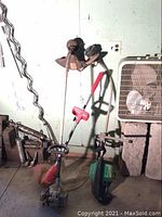 Three weed eaters leaning against a wall showing overall condition and setup.