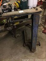 Full view of the antique weigh scale on wheels showing the metal frame, wooden balance beam, and wheels.