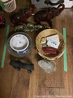 Overview photo showing all items together including wooden elephants, brass elephant figure, wicker basket, dog bowls, and glass bowl.