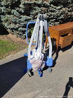 Folded patient lift frame with casters and slings gathered at base