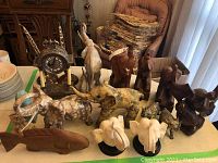 Overview of lot contents: mantel clock with candelabra, Lladró porcelain elephant, assorted resin and wood elephant figurines, carved fish