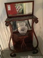 Antique wooden stand with attached mirror, curved legs, and lower shelf holding two etched glass bowls.