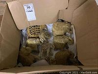 Top-down view inside a cardboard box showing seven onyx elephant figurines of varying sizes with detailed carvings and natural stone finish.