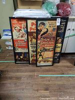 Four framed vintage movie posters leaning against a wall, each approximately 14x36 inches.