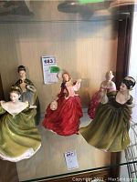 All five figurines grouped on glass shelf