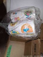Plastic-wrapped roll of stickers featuring colorful Smurf images, close-up view.