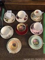 Eight assorted tea cup and saucer sets arranged on table