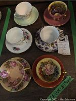 Overview of six bone china teacup and saucer sets on wooden surface