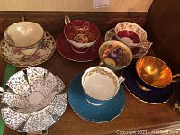 Overview of six teacup & saucer sets on wooden surface