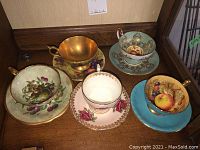 Group of five assorted tea cup and saucer sets showing various patterns and colors