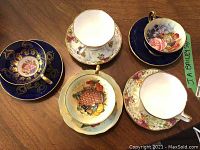 Overhead view of five teacup and saucer sets arranged on wood surface