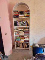 Front view of white wicker bookshelf filled with books.