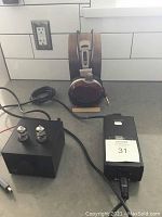Headphones on wooden stand beside amplifier and power supply brick
