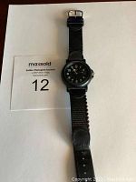 Front view of Swiss Army men's watch with black dial and fabric strap laid flat.