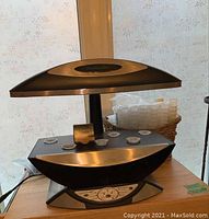 Full view of AeroGarden Pro100 system with light hood, planting tray with six pod sites, and control panel on wooden surface