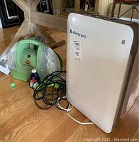 Photo showing the Bissell Little Green Rug Cleaner in green and the Allergy Pro air purifier in white placed on wooden floor.