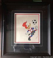 Framed Woody Woodpecker cel of character kicking a soccer ball, showing overall framing and matting.