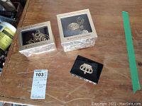 Two ornament boxes and crown case on wooden surface