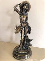 Full view of bronze sculpture showing entire figure on round base