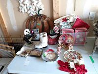 Table display of assorted Christmas decor including Santa figurines, collector plates, candy dish, porcelain skates, and small decorations.
