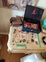 Full view of jewelry collection displayed on table and inside Rochas jewelry box including necklaces, earrings, bracelets, and brooches.