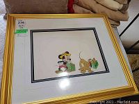 Full view of framed cel showing Mickey Mouse and Pluto with green suitcases; frame is gold and measures 22 by 24 inches.