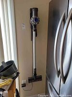 Vacuum hung on wall mount with main unit, wand and floor head visible