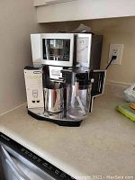 Front-left angled view showing machine with EcoDecalk box and frothing jug