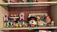 Full view of shelf with Enesco Mickey Mouse musical figurine, miniature chairs and table, Czechoslovakian tray, pig figurine, and small decorative birds and flowers.