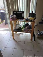 Full view of the pine shelf holding various household items including the Foodsaver vacuum sealer on top, folded towels, and plastic containers on the bottom shelf.