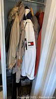 Jackets hanging in closet showing beige, tan, white and patterned jackets.