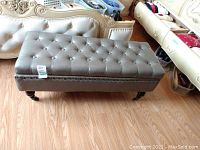 Full front view of grey tufted bench showing overall design and condition