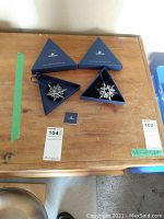 Two Swarovski annual ornaments, 2006 and 2007, each in original triangular blue boxes with certificates on a wooden table.