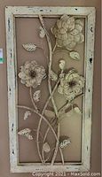 Full frontal photo of the rectangular wall art showing three large flowers with stems and leaves on a distressed white frame.