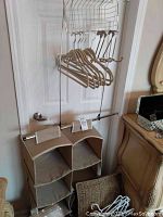 Metal rack over the door with wire basket and wooden hangers, showing storage setup
