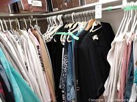 Women’s jackets and long sleeve shirts on hangers in assorted colors including gray, pink, tan, black, blue, and leopard print patterns.