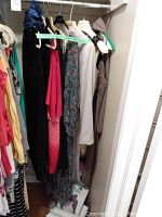 Closet view showing seven formal dresses hanging on a rod, different colors and styles including floral and solid color dresses.