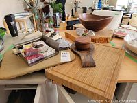 Five wooden kitchen and serving items arranged on a table including cutting boards, a wooden bowl, and utensils.