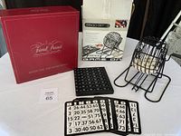 Photo showing Trivial Pursuit Baby Boomers Edition red boxed game with Bingo set box, bingo cards, ball holder, and numbered balls visible.