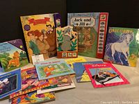 Wide shot of various children's books arranged on a surface showing titles including Jack and Jill, Beauty and the Beast, Unicorns, and The Lion King.