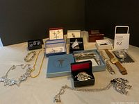 General overview of jewelry items on a table including necklaces, watches, bracelets, and brooches.