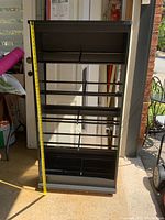 Full view of the black shoe rack with a measuring tape showing height.