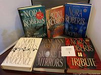 Front view of six hardcover books arranged in two rows, showcasing titles and authors on cover.