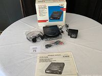 Full view of all items included in the lot: CD player, power adapter, headphones, RCA audio cable, and owner's manual, alongside original box.