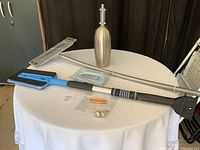 View of all items on round table showing Swiffer mop, snow scraper, toilet bowl cleaner container and small accessories.