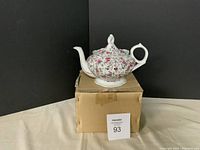 Full view of the teapot, floral design, placed on its original box.