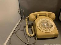 Photo of the rotary phone base showing the dial, cradle supports and cord attachment.