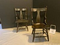Pair of wooden doll chairs side by side, showing front and side angles, on neutral backdrop
